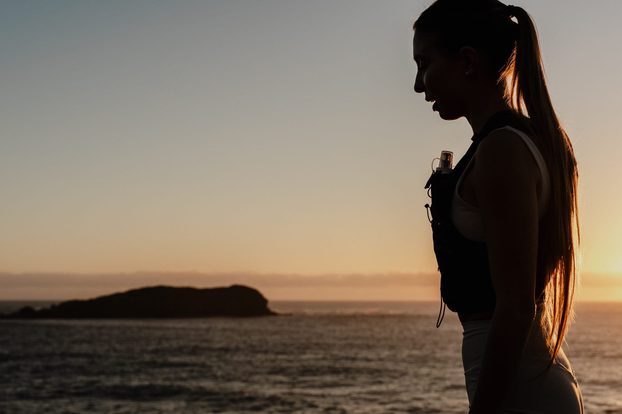 Trail runner pausing to look out over the ocean at sunset