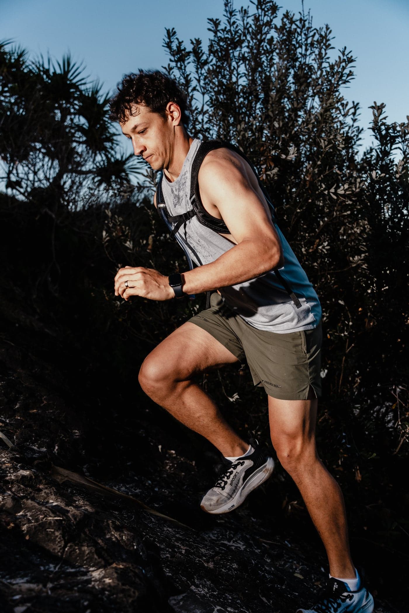 Trail runner powering up a rocky climb at sunset