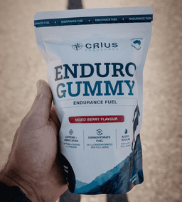 Hand holding an Enduro Gummy pouch outdoors, front label facing camera